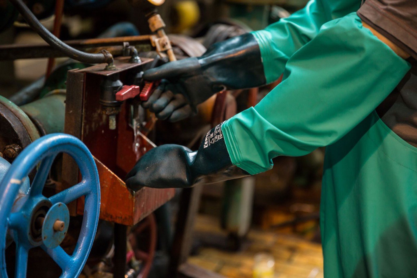 Gloved hands turning a valve