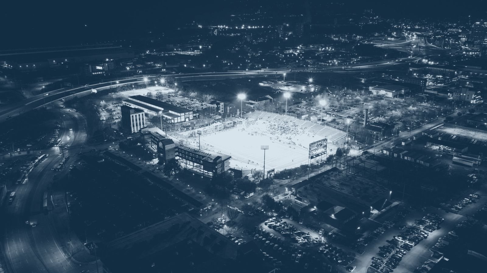 Aerial view of a floodlit stadium within a night time cityscape